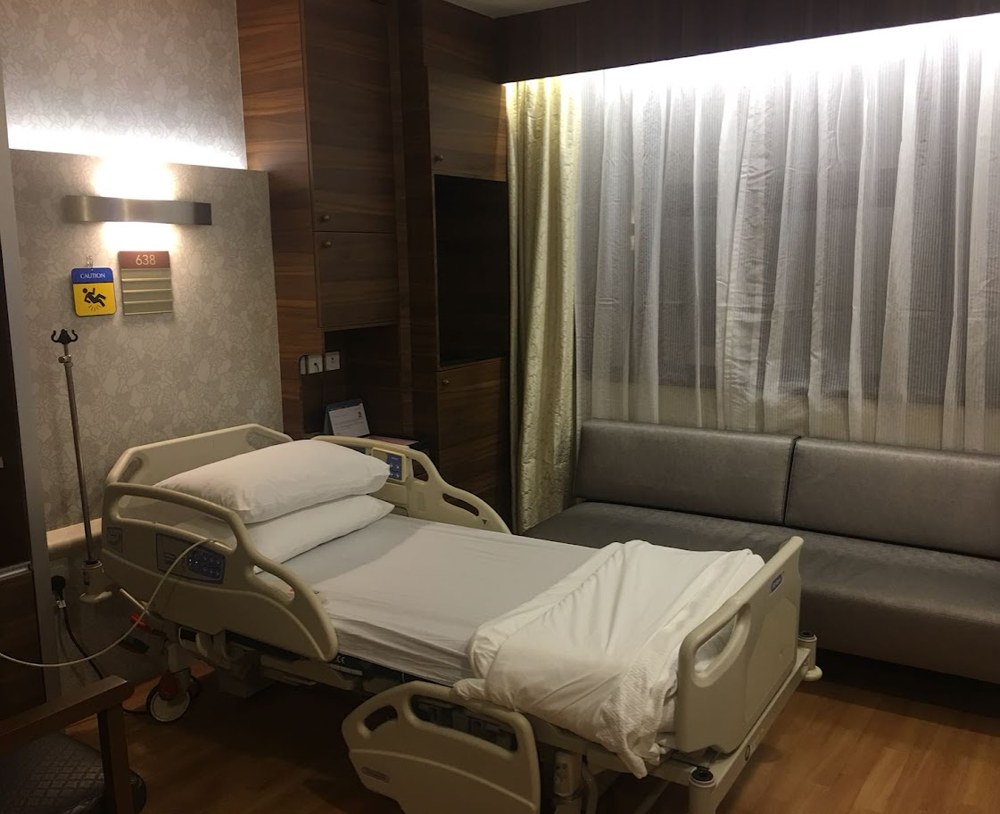 An empty hospital room with a bed and sofa